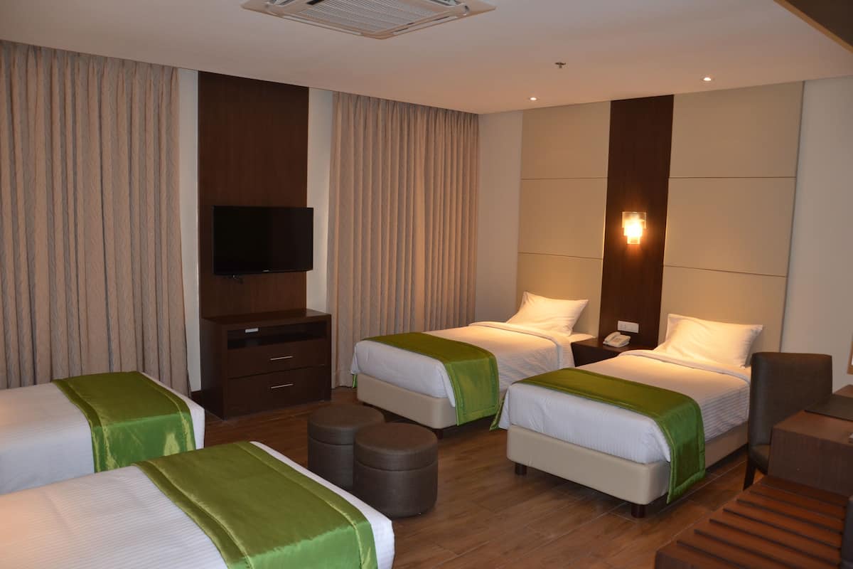 A hotel room with two single beds, a TV, a desk, and a chair.
