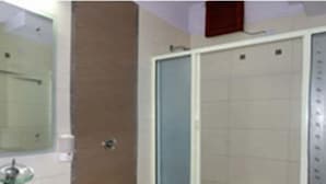 Une salle de bain avec un lavabo en verre, des toilettes blanches et un espace douche.
