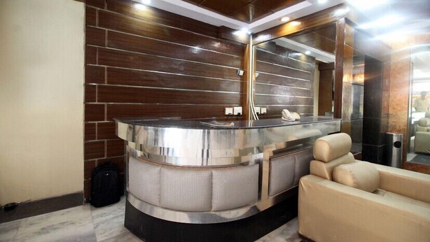 Un espace d’accueil moderne, doté d’un comptoir d’accueil incurvé, d’un grand miroir et d’un canapé beige.