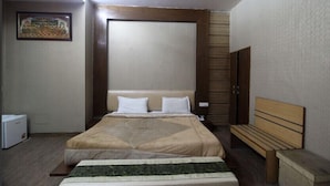 Une chambre d’hôtel avec un grand lit, un banc, une petite table et un tableau au mur.