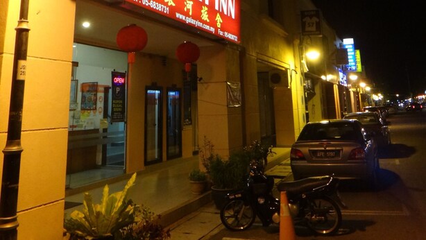 A building with a sign for Galaxy Inn, featuring a contact number and website. - Galaxy Inn (Lumut)