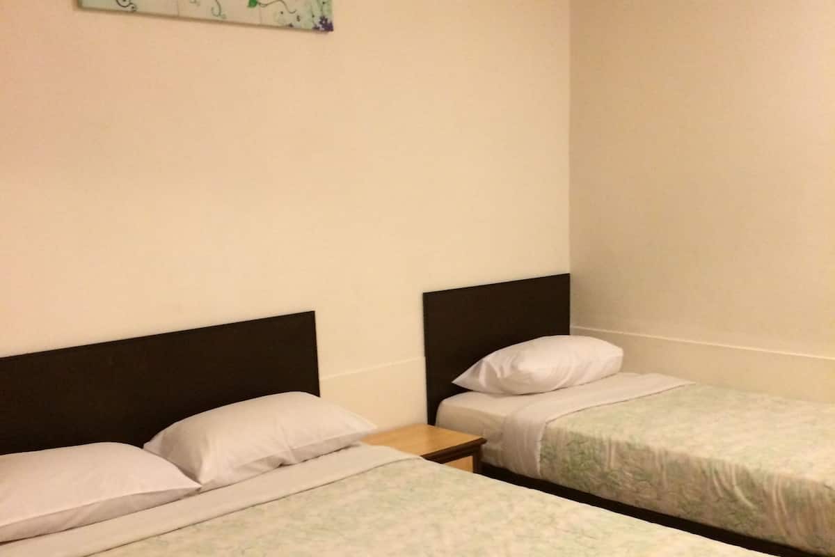 A hotel room with two beds, each with a floral-patterned bedspread, a nightstand, and a wall-mounted artwork.
