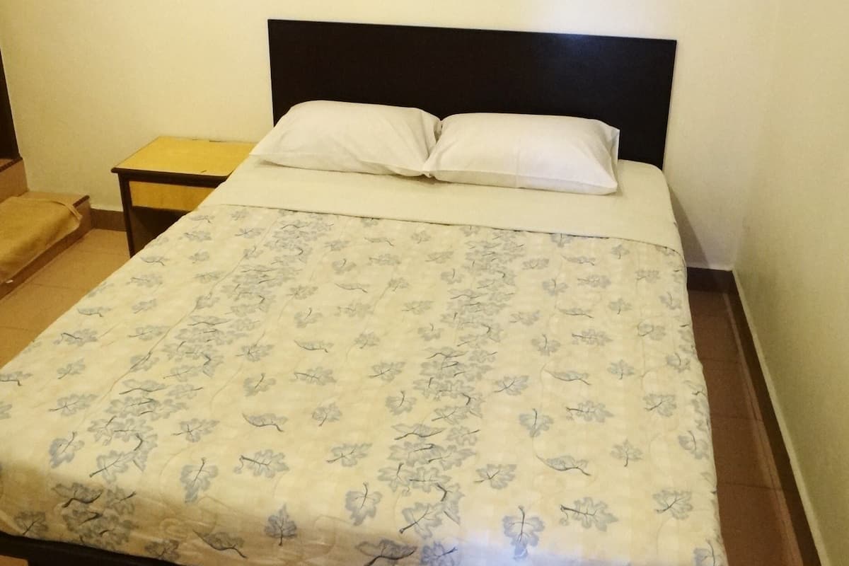 A bed with a floral bedspread, a small bedside table, and a painting on the wall.