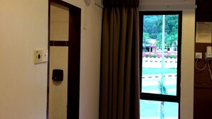 A room with a window, a door, an air conditioning unit, and a wall-mounted fan. - Galaxy Inn (Lumut)