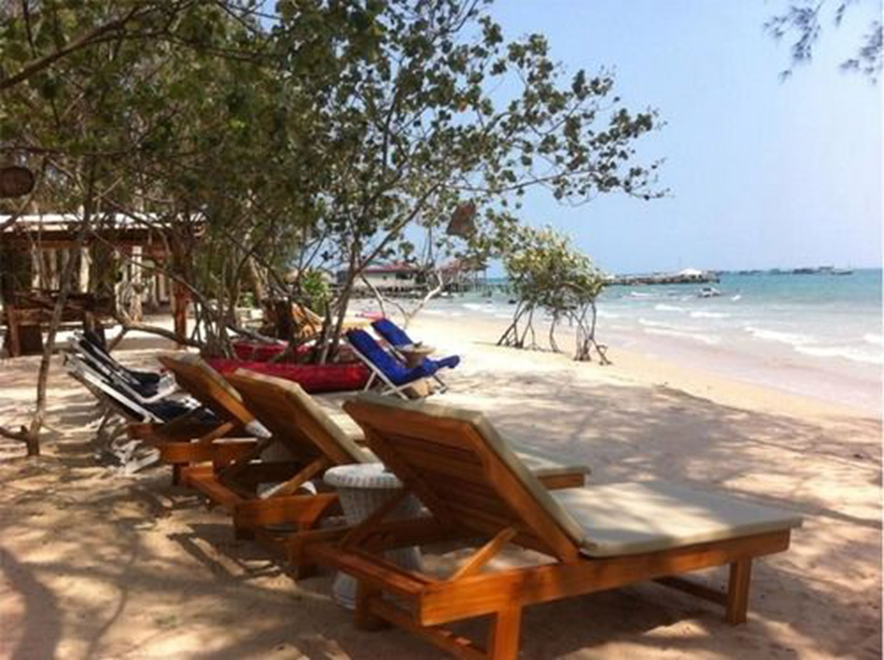 A beach with wooden lounge chairs and a small hut.