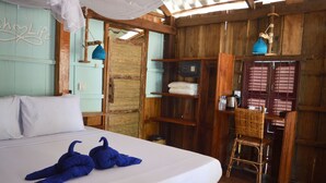 Een houten kamer met een bed, een stoel en een plank met handdoeken.