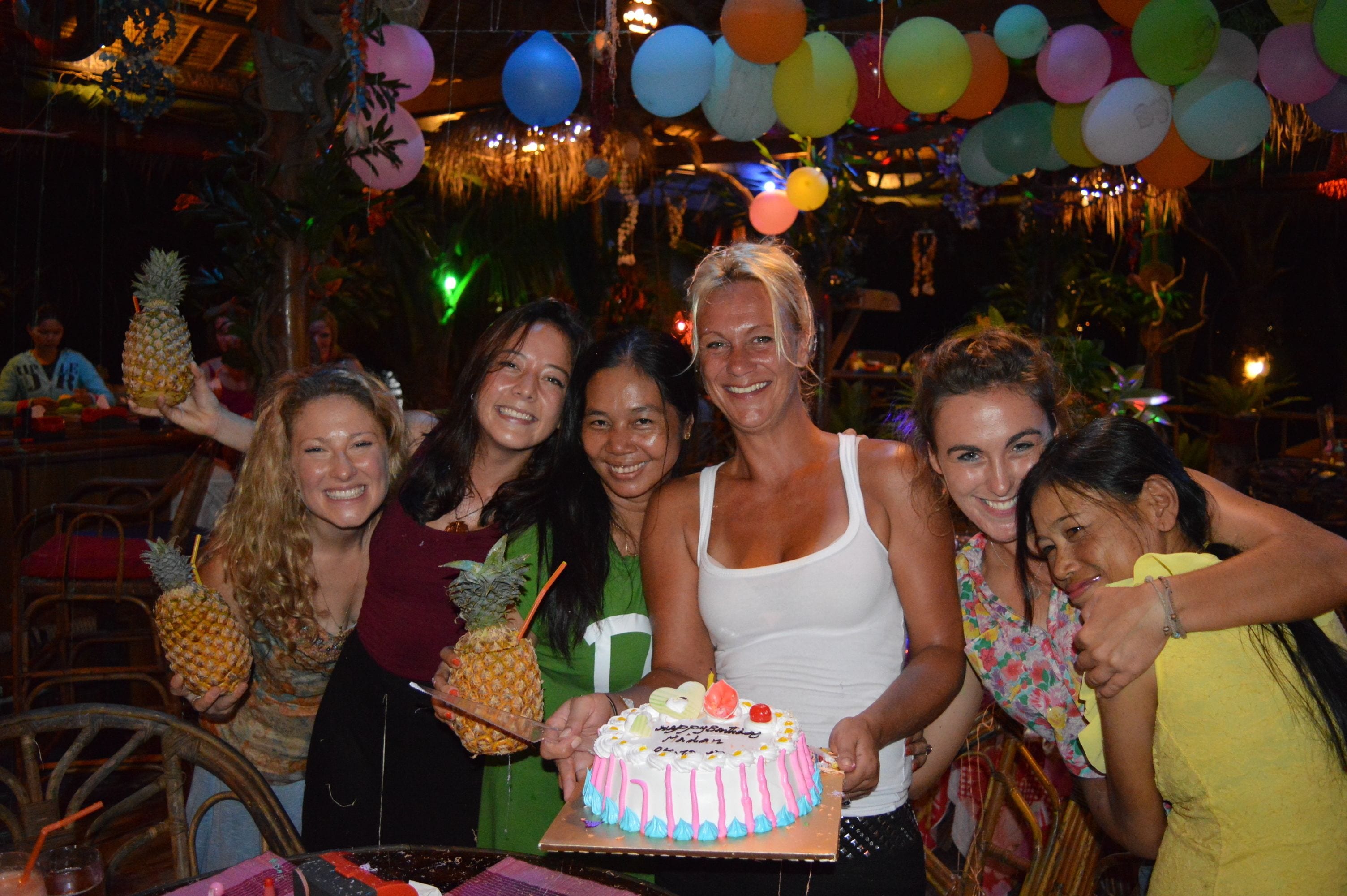 Un grupo de personas en una fiesta, con un pastel y globos.