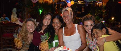 Un groupe de personnes à une fête, avec un gâteau et des ballons.