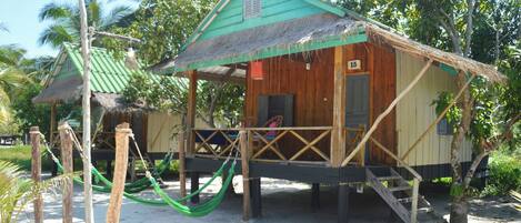 Una casa de madera con techo de paja, un porche y el número 15 en la puerta.