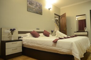 A neatly made bed with white and brown bedding, a bedside table with a vase of flowers, and a painting on the wall. - Zermatt Hotel (Tanah Rata)
