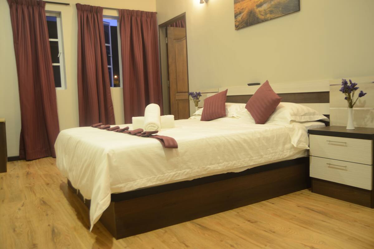 A hotel room with a bed, a nightstand, a mirror, and a painting on the wall.