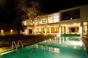 Un bâtiment moderne avec une piscine, de nuit.