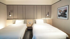 Ein Hotelzimmer mit zwei Betten, einem Nachttisch, einer Wandleuchte und einem gerahmten Bild.