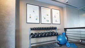 Ein Fitnessraum mit Kurzhanteln, einem blauen Trainingsball und Yogamatten.
