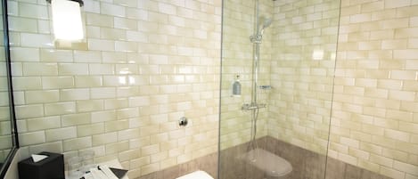 Ein modernes Badezimmer mit einer Glaskabine zur Dusche, weißen Fliesenwänden und einer weißen Toilette.