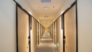 Ein Hotelgang mit Türen an beiden Seiten, einem Teppichboden und einer Decke mit eingelassenen Leuchten.
