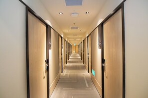 Ein Hotelgang mit Türen an beiden Seiten, einem Teppichboden und einer Decke mit eingelassenen Leuchten.