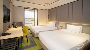Een hotelkamer met twee bedden, een bureau, een stoel en uitzicht op het omliggende landschap.