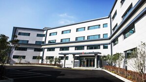 A modern hotel with a flat facade, multiple windows, and a parking lot. - Ra Hotel (Jeju City)