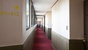 A hotel corridor with a red carpet, a directional sign indicating room numbers 501-512, and a door on the right. - Ra Hotel (Jeju City)