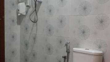 A bathroom with a toilet, a shower unit, and patterned tiles.