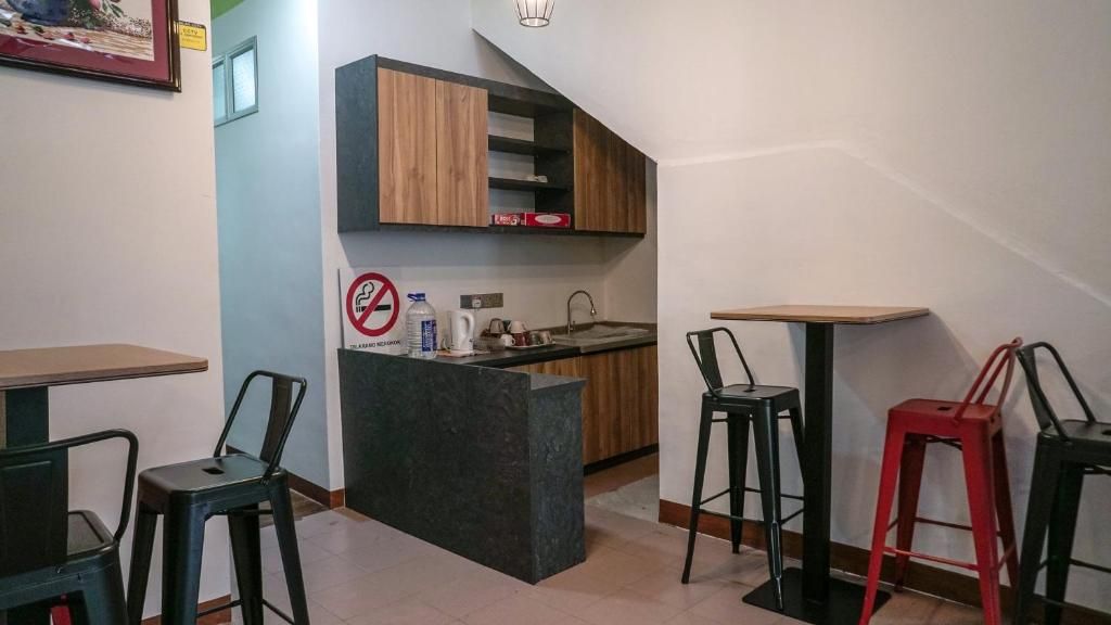 Cocina compacta con isla integrada, lavamanos y encimera pequeña. Hay dos taburetes y una mesa con sillas.