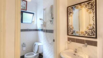 A bathroom with a toilet, shower, and sink.