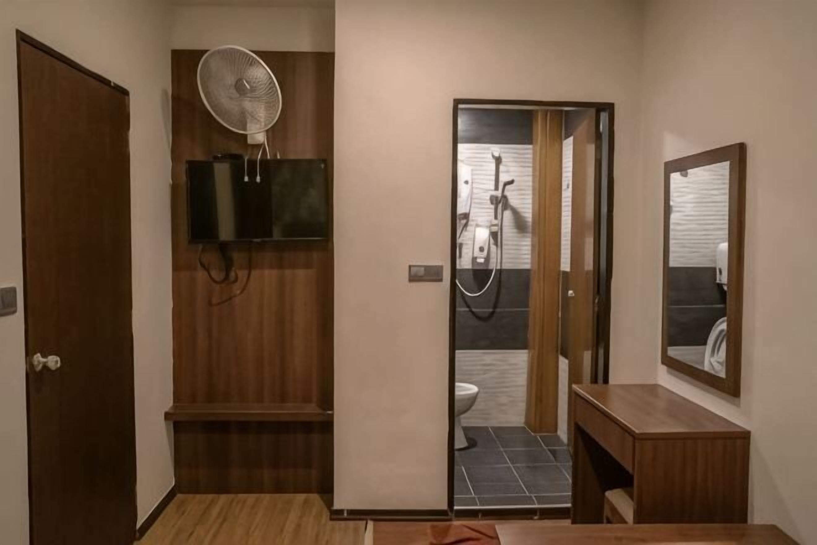 A bathroom with a shower, a fan, a mirror, and a television.