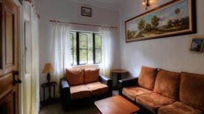A room with two leather sofas, a small round table, a lamp, and a window with curtains.