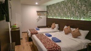 A hotel room with two beds, a bedside table, a TV, and a wall-mounted shelf. - Highlanders Hotel (Tanah Rata)