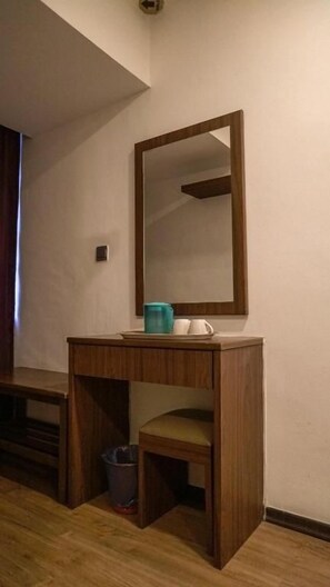 A wooden desk with a mirror, a trash bin, and a blue cup. - Highlanders Hotel (Tanah Rata)