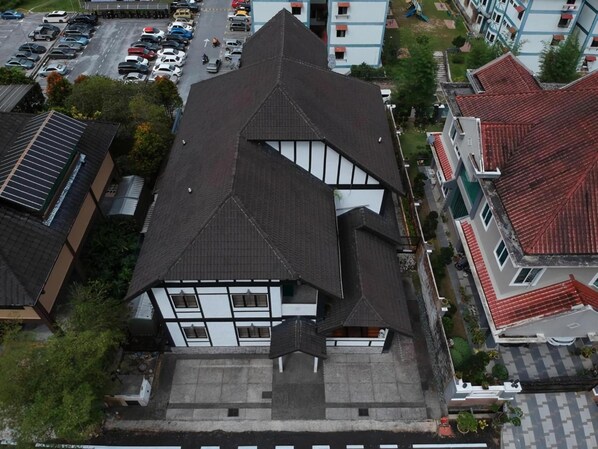 A multi-story building with a steeply pitched roof, large windows, and a flat roof section.
