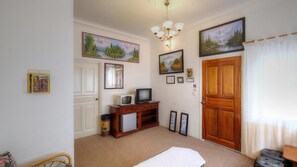 A room with a wooden door, a television on a wooden cabinet, and framed pictures on the walls.