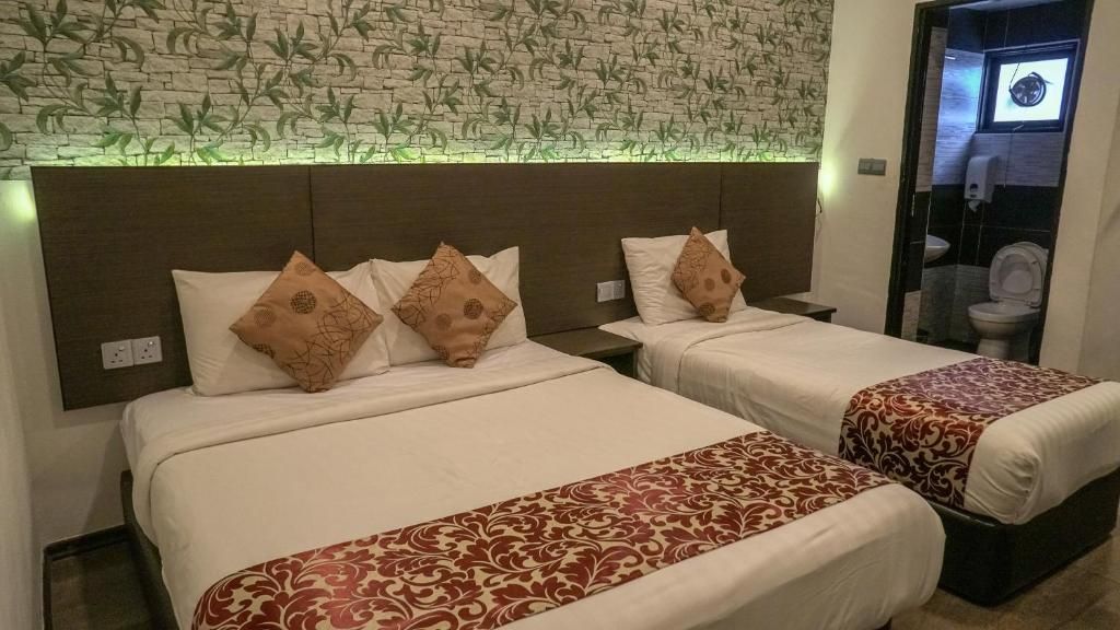 Una habitación de hotel con dos camas, cada una con una colcha estampada y almohadas a juego.