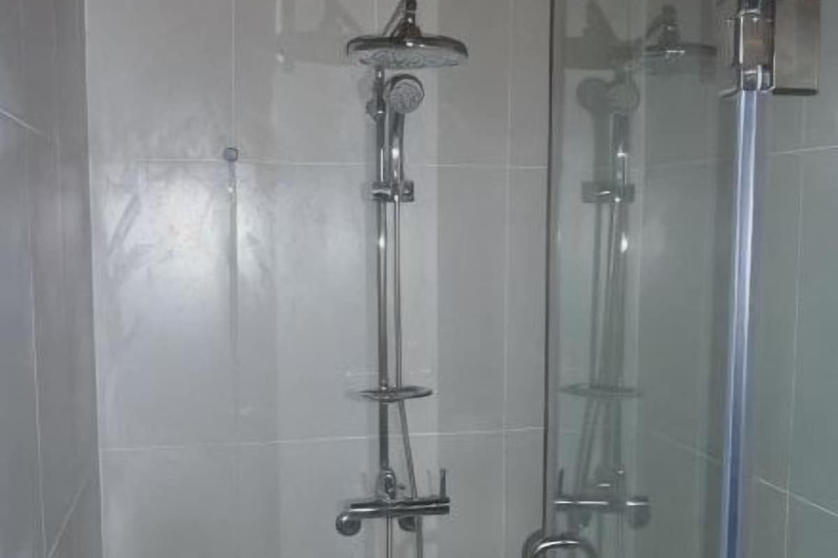 Een douche met glazen wand en chroombeslag.