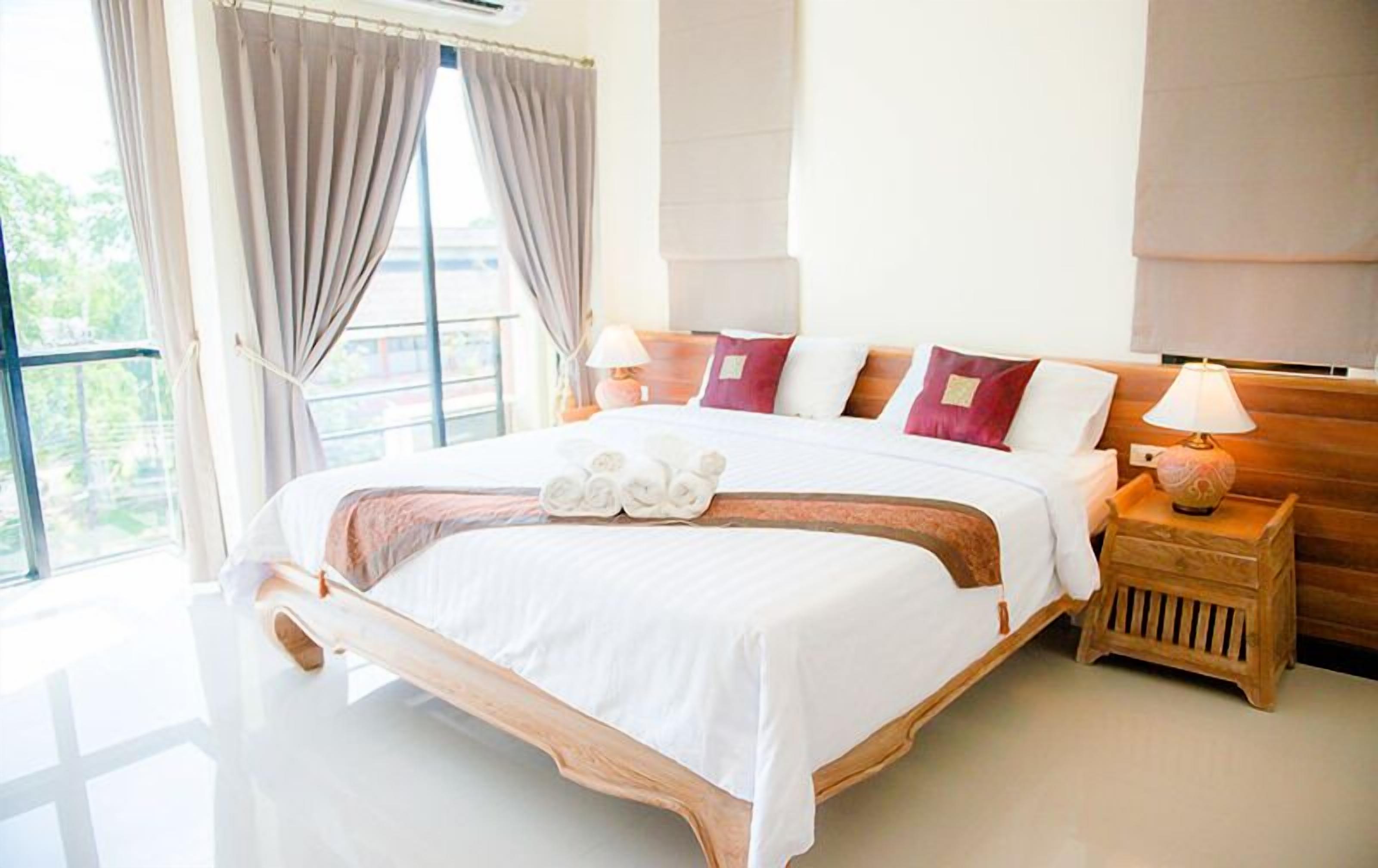 Amplia habitación de hotel con una cama grande, una mesita de noche de madera y vistas a zonas verdes.