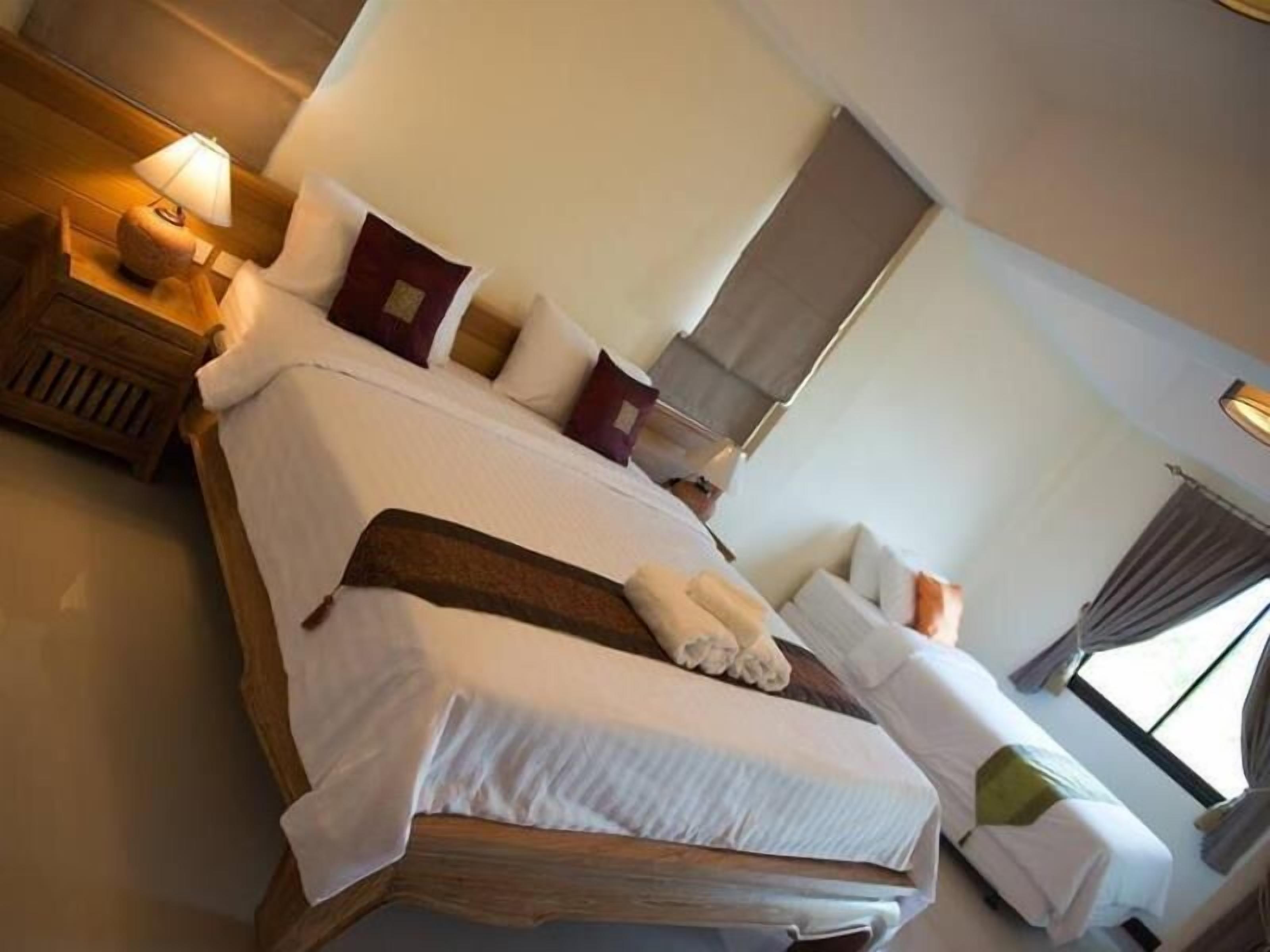 Une chambre d’hôtel avec un grand lit, une table de chevet avec une lampe et une fenêtre avec des rideaux.