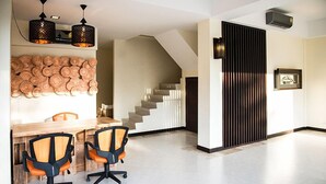 Un interior moderno con comedor, dos sillas de escritorio, una escalera y una lámpara fijada a la pared.