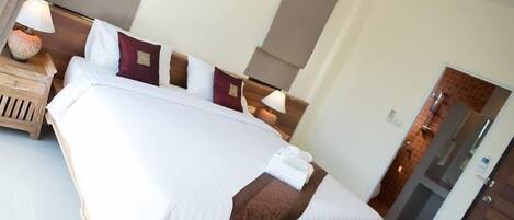 A neatly made bed with white and brown linens, a wooden headboard, and a bedside table with a lamp and a decorative item.