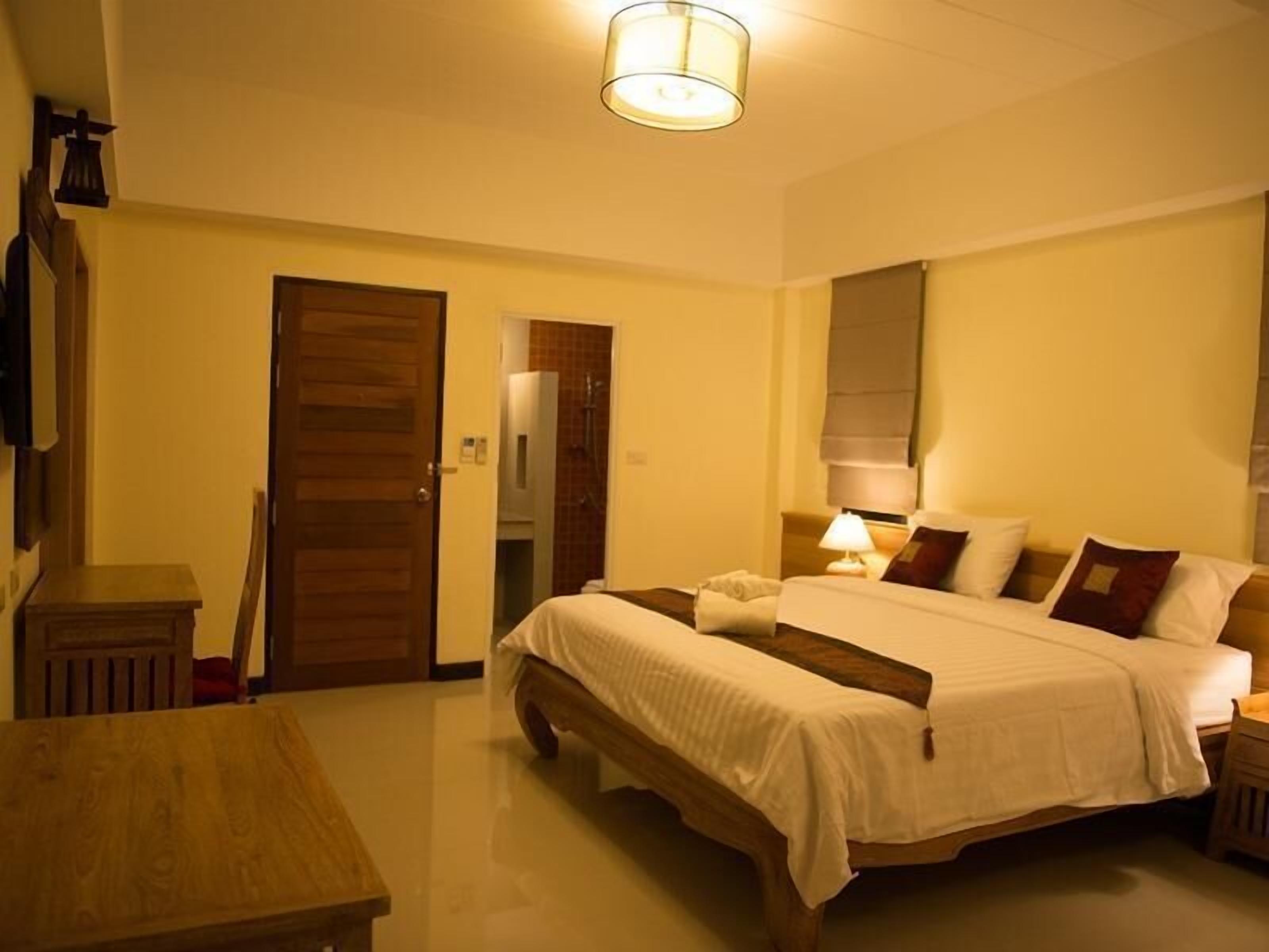Une chambre à coucher avec un lit, des tables de chevet, une lampe, une porte en bois et un miroir.