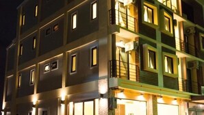 Un hotel de varios pisos con ventanas e balcones iluminados.
