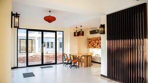 Amplia habitación con un gran ventanal corredero que da a un espacio exterior, una mesa de comedor de madera con sillas y una lámpara de techo moderna.