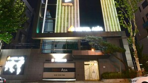 A hotel building with vertical LED light displays and a sign reading "Hotel Asia".