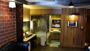 A modern bathroom with a glass shower enclosure, a wooden vanity, and a black leather chair.