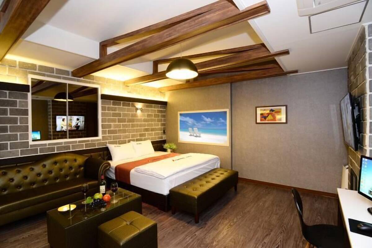 A hotel room with a bed, a sofa, a desk, and a TV.