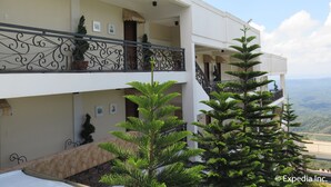 A two-story building with balconies, potted plants, and a view of the landscape. - Splash Suites Hotel Tagaytay (Tagaytay)