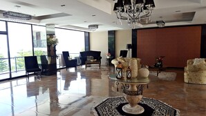 A spacious lobby with a high ceiling, a chandelier, and a large window offering a view of greenery. - Splash Suites Hotel Tagaytay (Tagaytay)