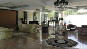 A spacious lobby with a high ceiling, a chandelier, and a large window offering a view of the outside. - Splash Suites Hotel Tagaytay (Tagaytay)
