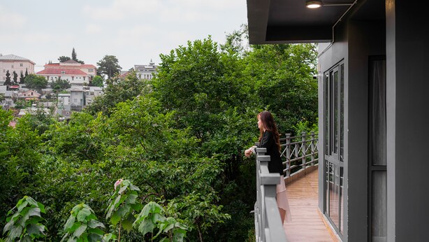 A balcony with a view of a lush green area and buildings in the background. - Hong Mon Resort Da Lat (Xuan Huong - Da Lat)