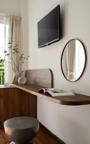 A modern bathroom with a wooden vanity, a round mirror, a flat-screen TV, and a stone basin. - Hong Mon Resort Da Lat (Da Lat)